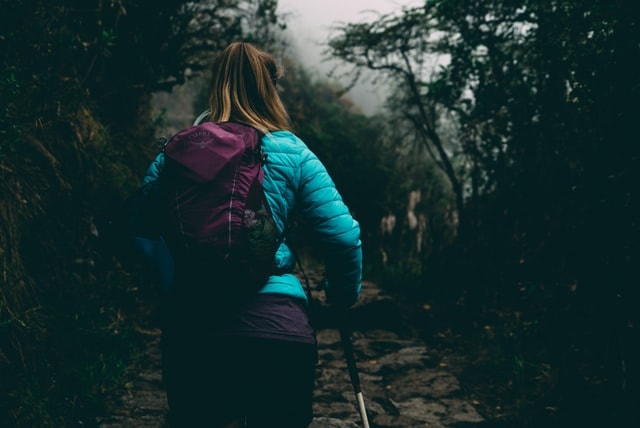 girl in teal jacket hiking with poles