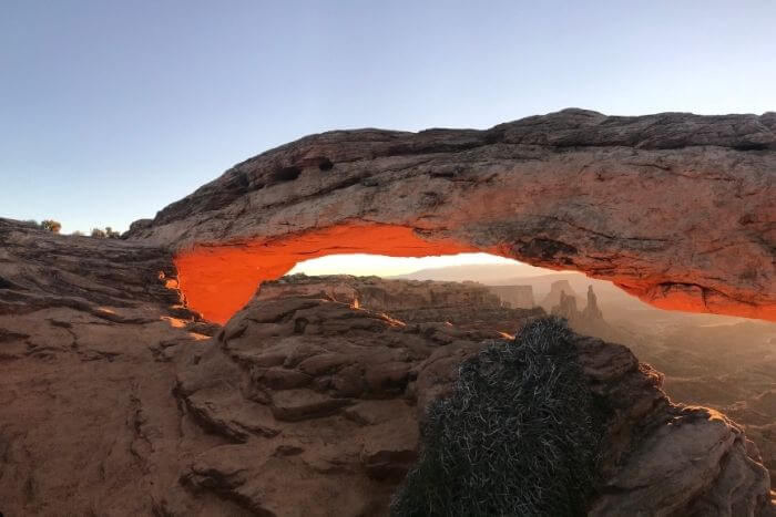 arch lit up orange as the sun rises