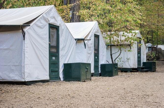 three canva tents with green front doors in a row